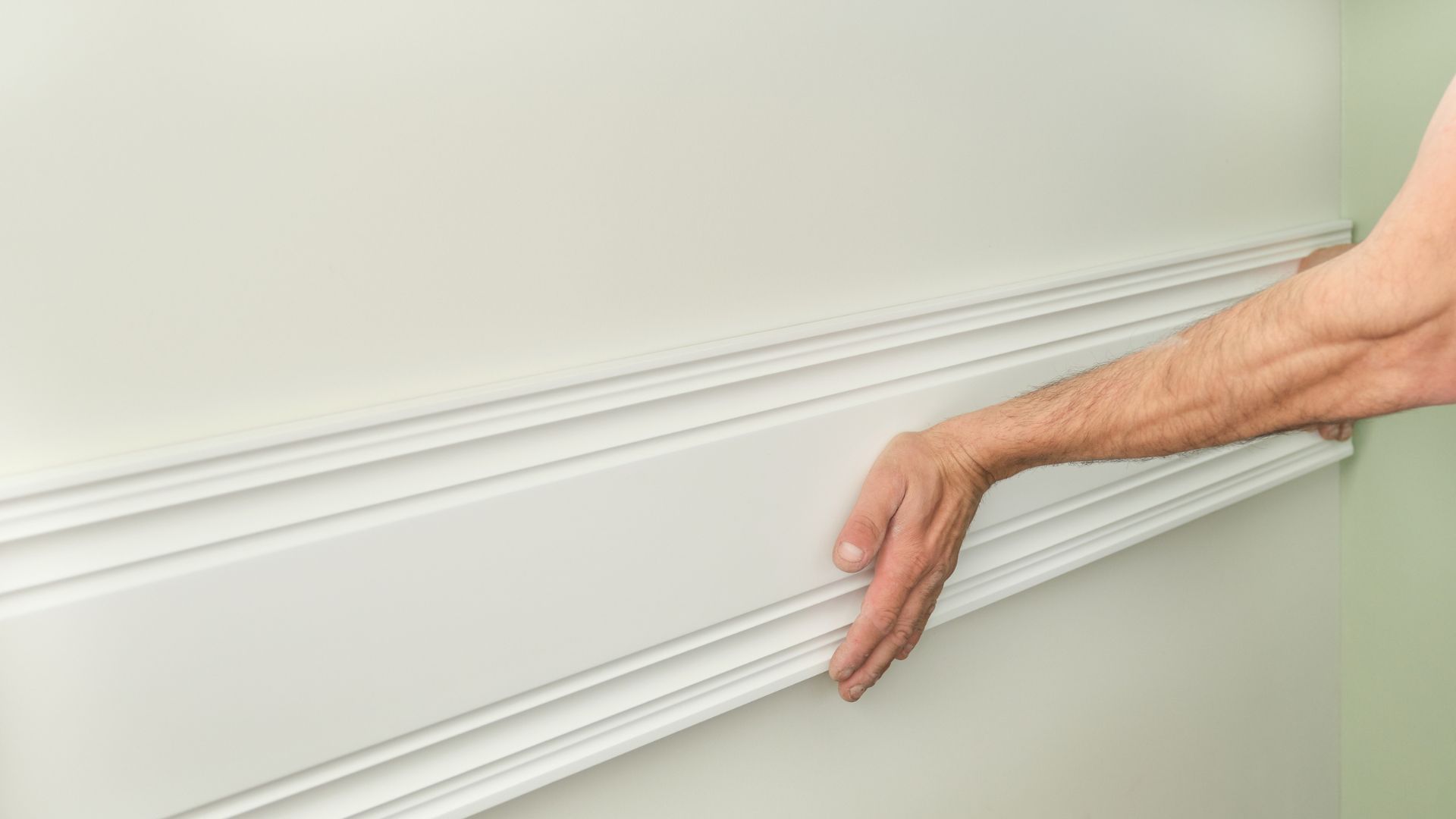 Hand touching white textured wall with decorative molding