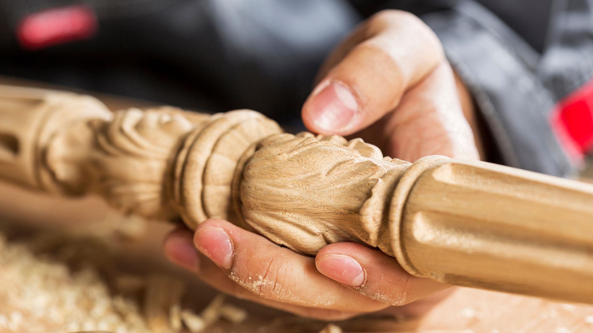 Hands carving intricate wooden details on decorative wooden spindle