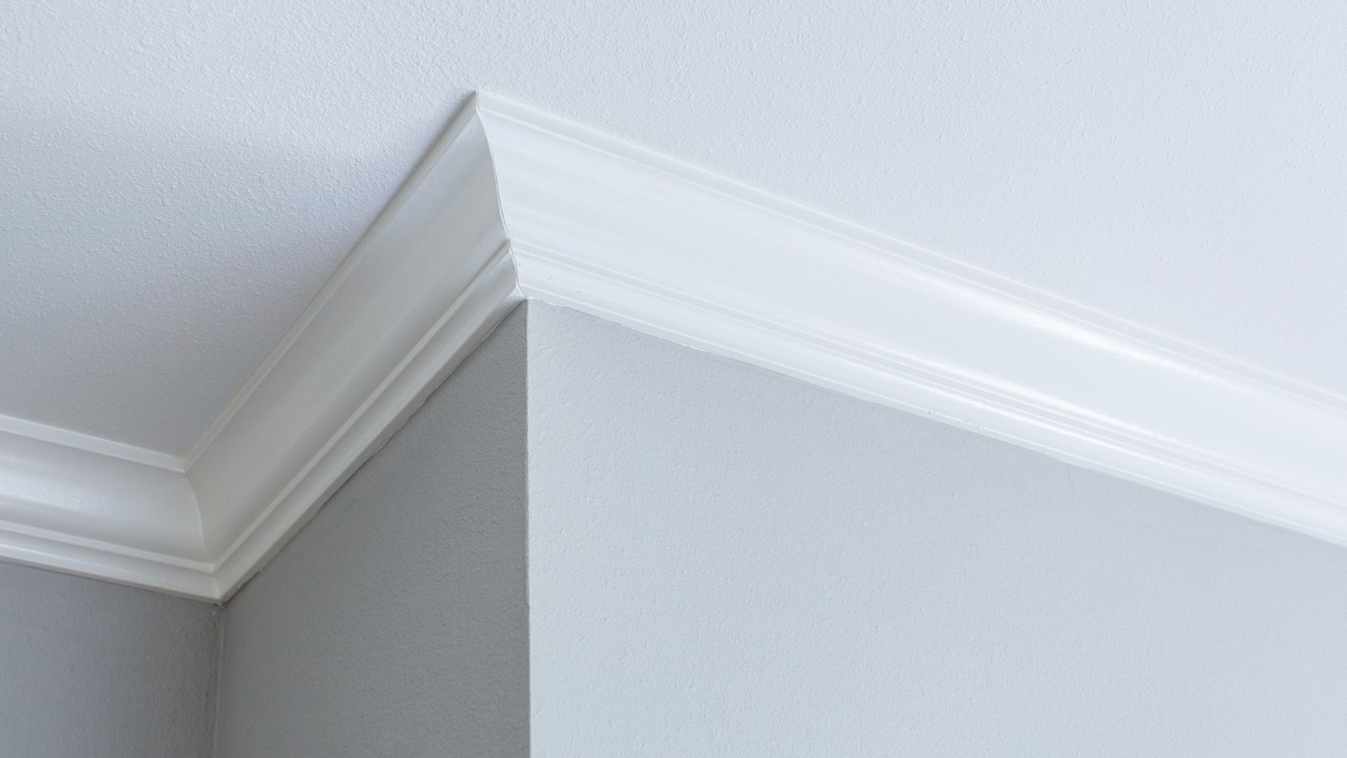 White crown molding meeting gray and white wall at corner