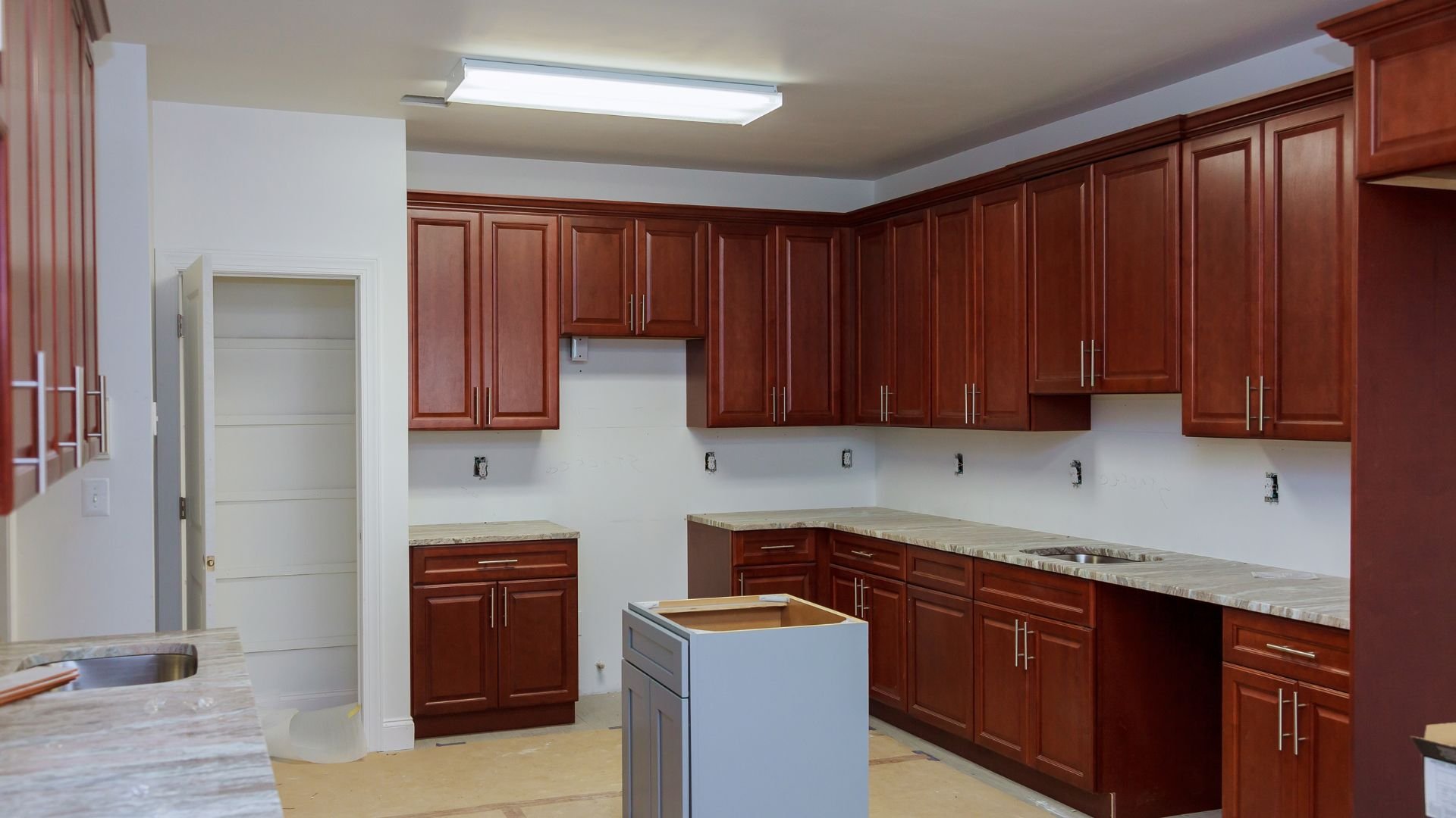 New kitchen with cherry wood cabinets, marble countertops, and center island