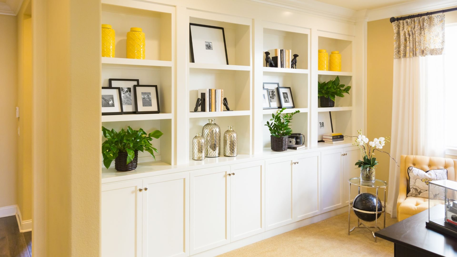 White built-in shelves with yellow accents, decorative objects, and green plants
